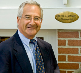 Keith Yankow stands by a brick wall in formal attire.